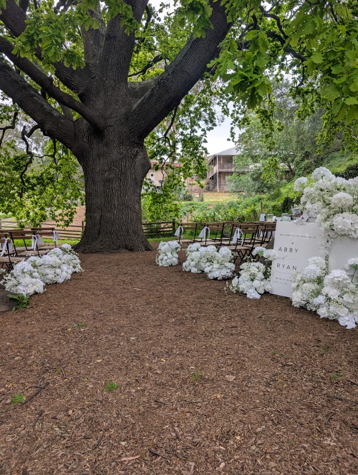Garden ceremony aisle under tree with florals