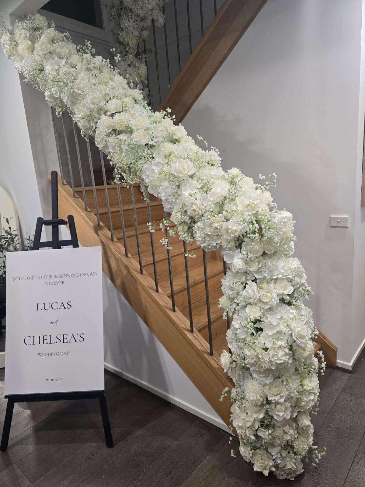 Staircase with cascading floral garland and welcome sign